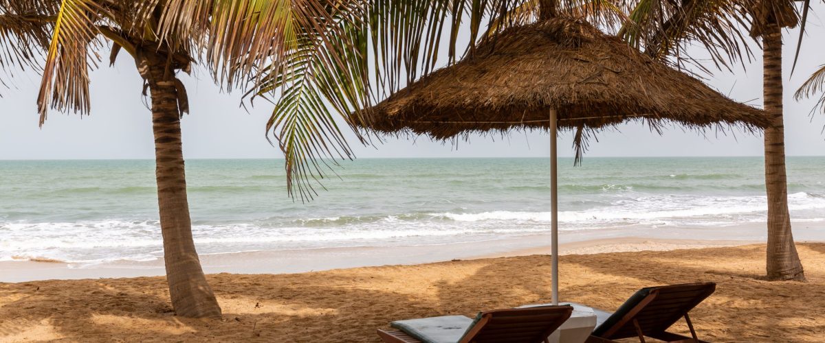 beach-gambia-with-thatch-umbrellas-palms-beach-chairs-with-sea-background (1)